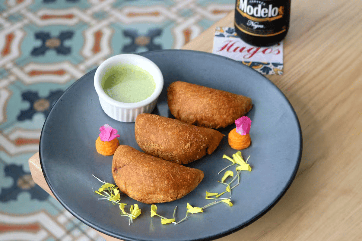 Crispy beef tail empanadas served with dipping sauce and fresh garnishes at Hugo's restaurant.