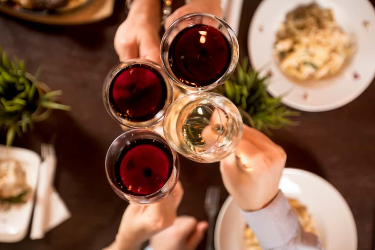 Four friends toasting white and red wine glasses over dinner