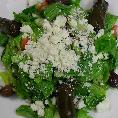 mixed greens with a variety of vegetables and crumbled cheese on top