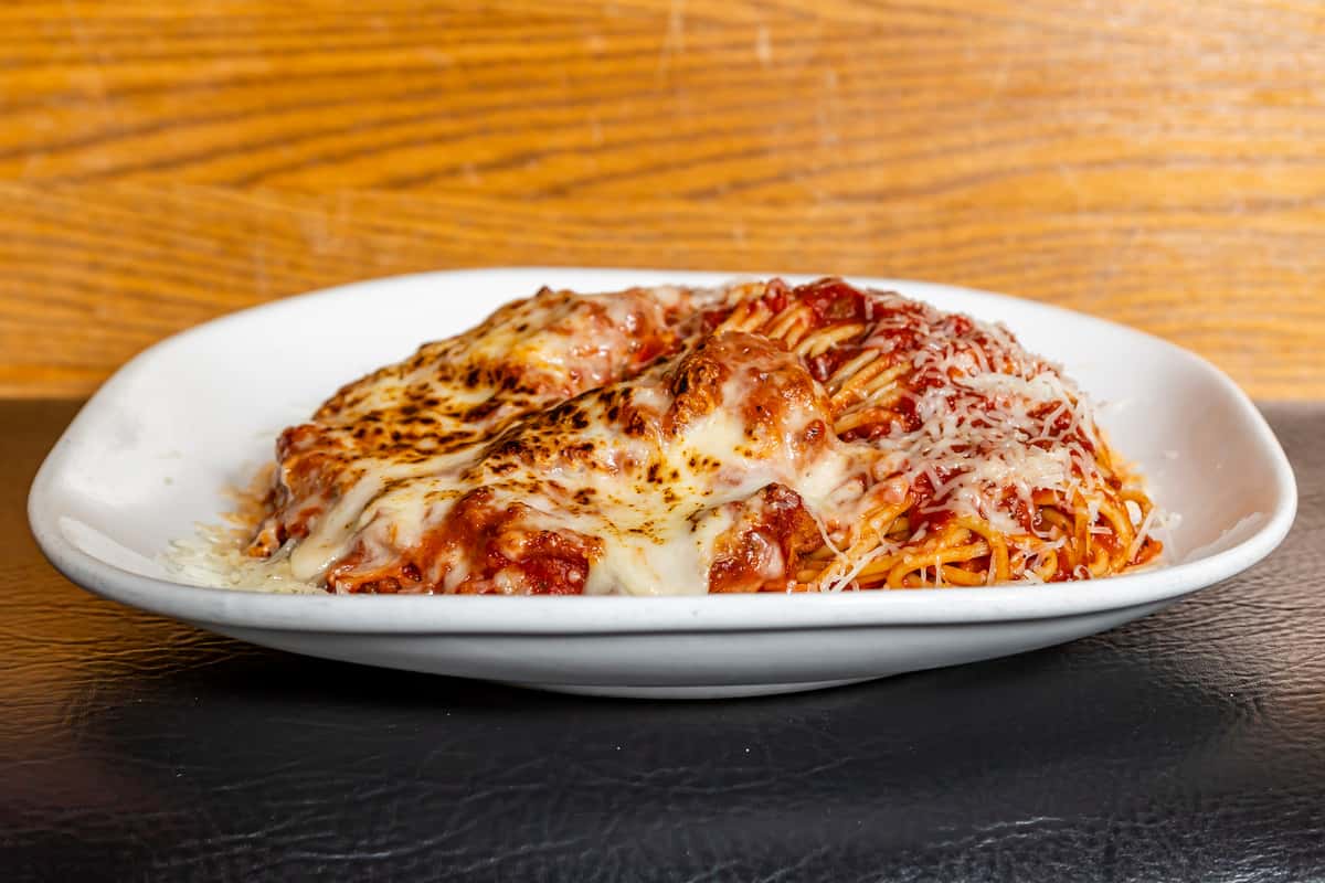 Chicken Parmesan served over pasta with marinara and melted cheese at Gorat's Steak House