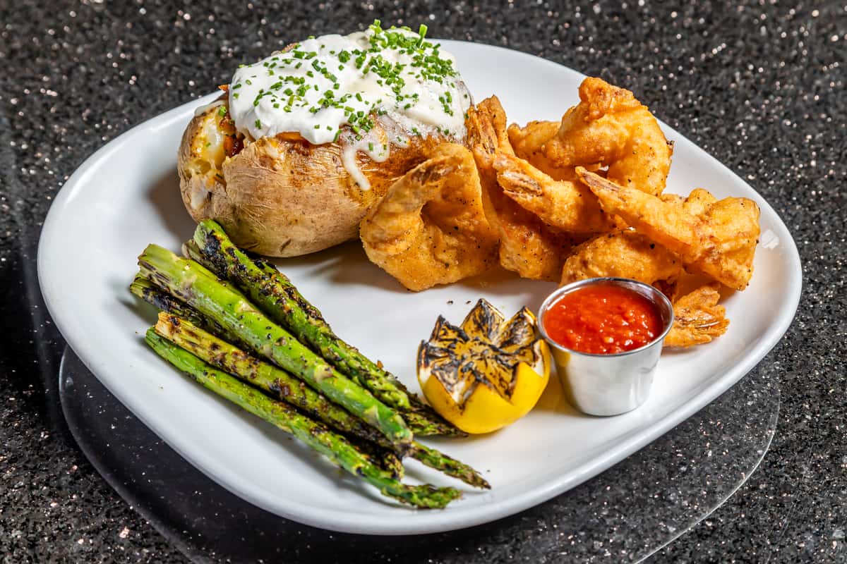 Crispy tempura shrimp with loaded baked potato, asparagus, grilled lemon, and dipping sauce at Gorat's Steak House
