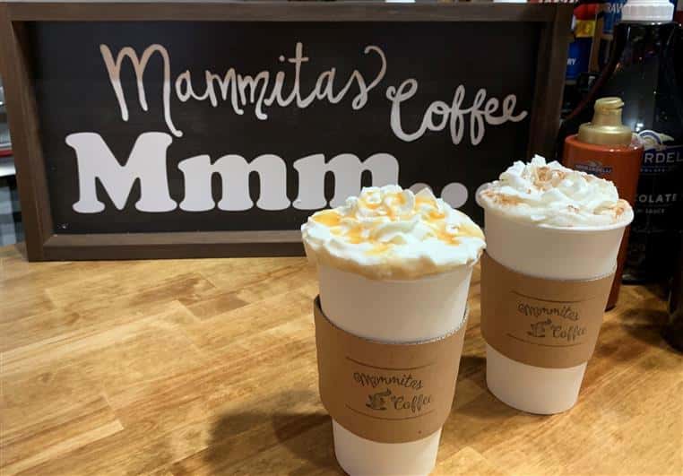 two lattes with whipped cream on countertop with Mammitas Coffee sign