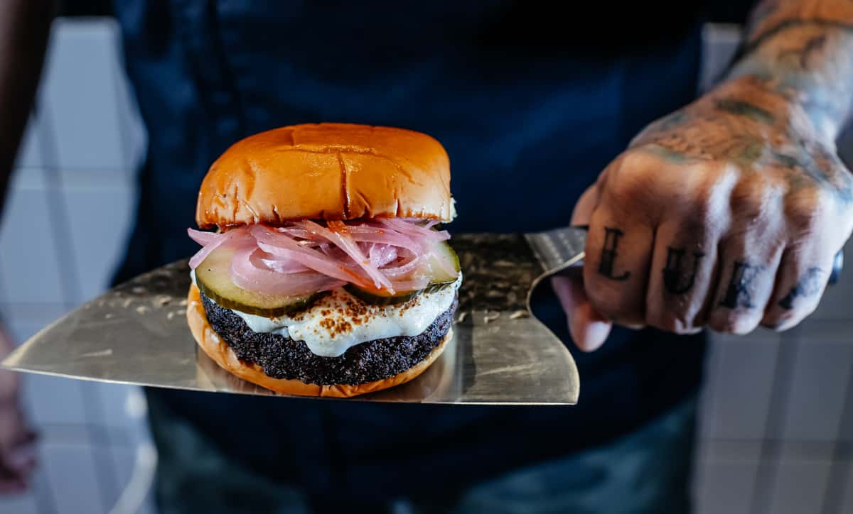 crew member holding burger on large knife