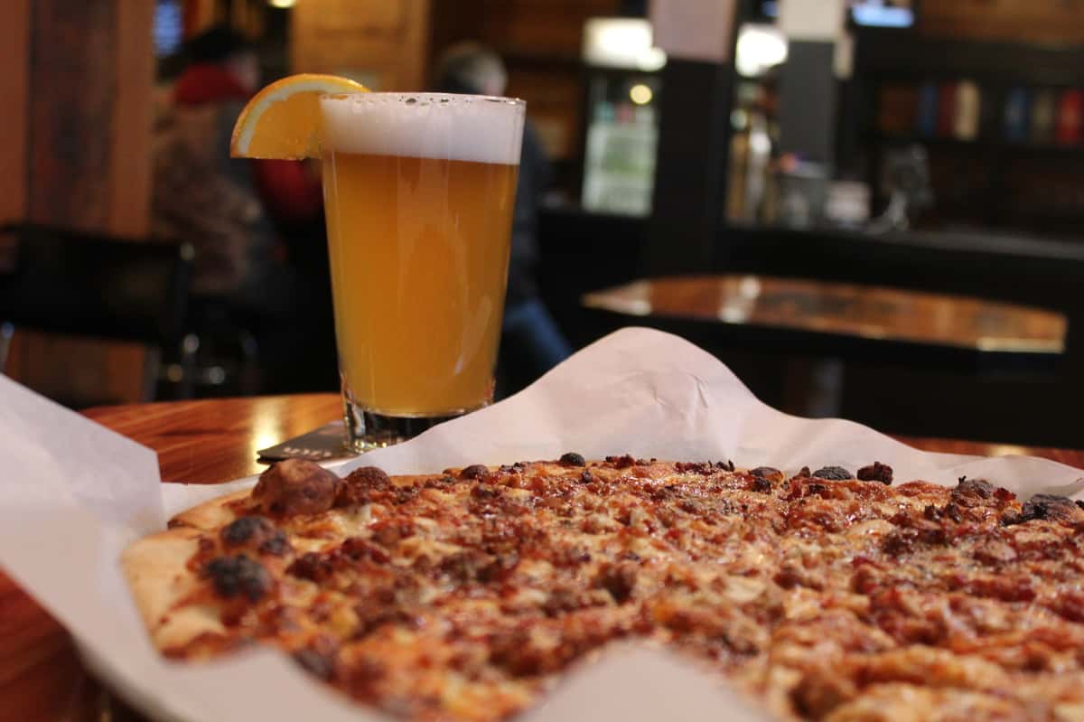 Pizza on a parchment sheet with a pint of beer