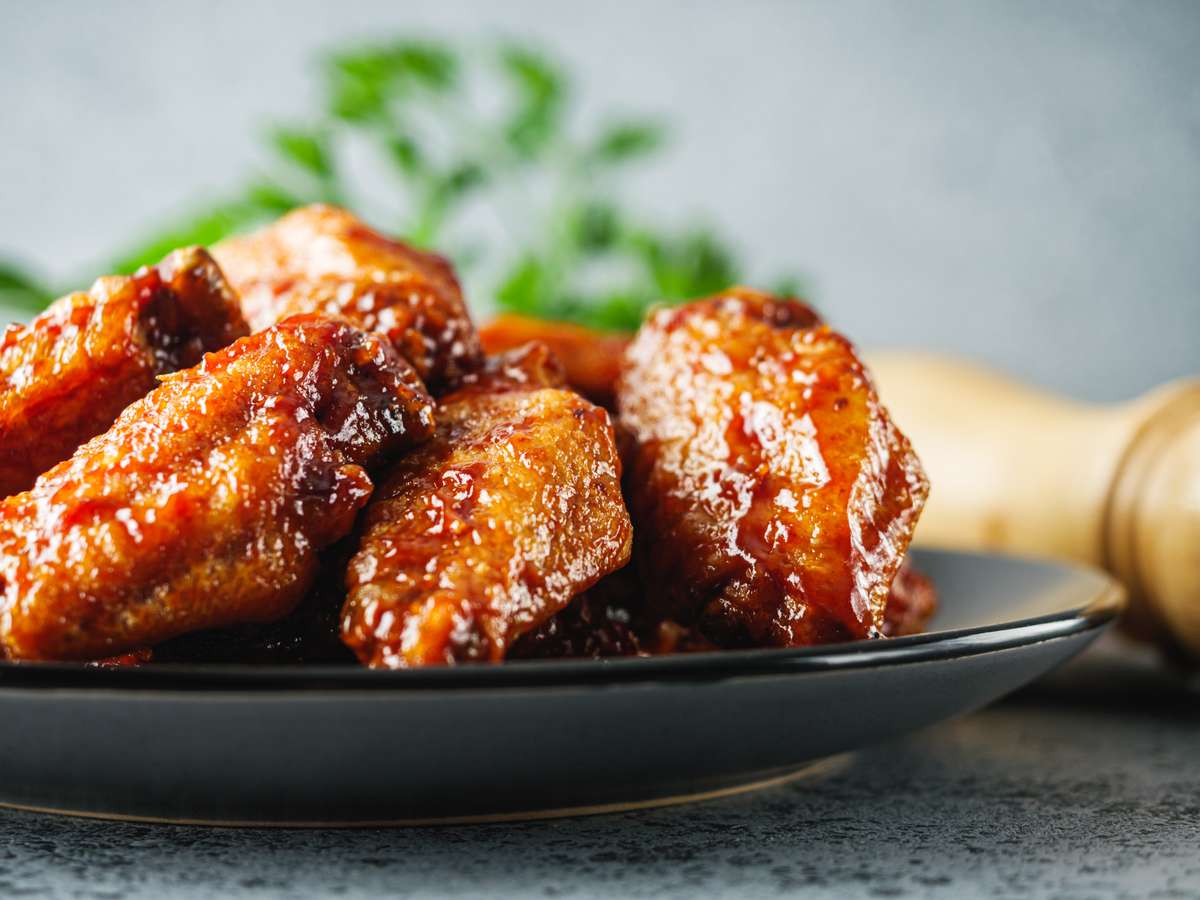 Close-up of spicy buffalo wings coated in sauce on a dark plate