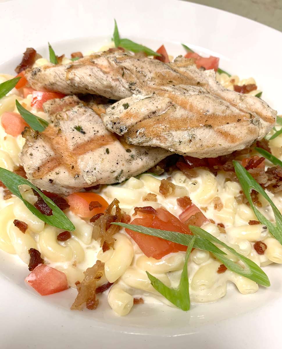 Grilled or fried chicken over elbow macaroni in a creamy white cheddar sauce, topped with bacon, tomato & scallions