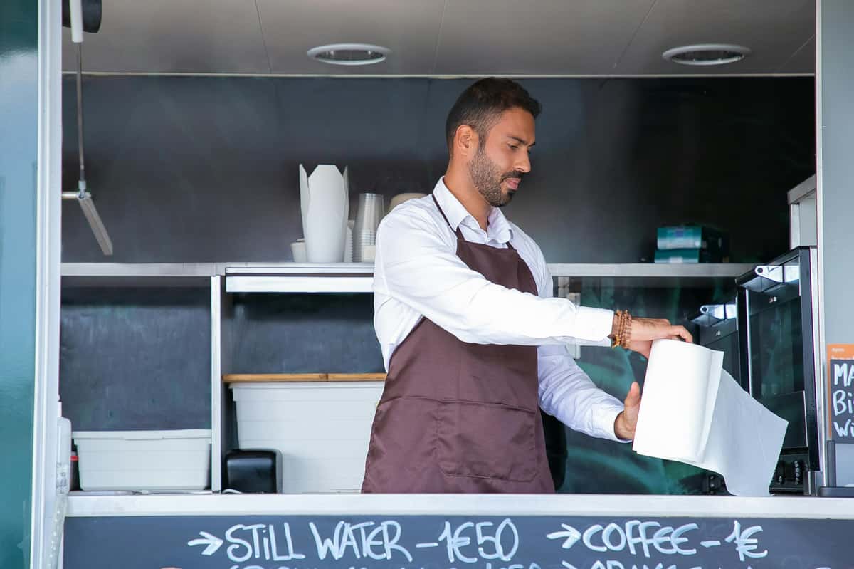 A Pierce Creek employee in an apron is seen taking a paper towel from a roll in the food truck.