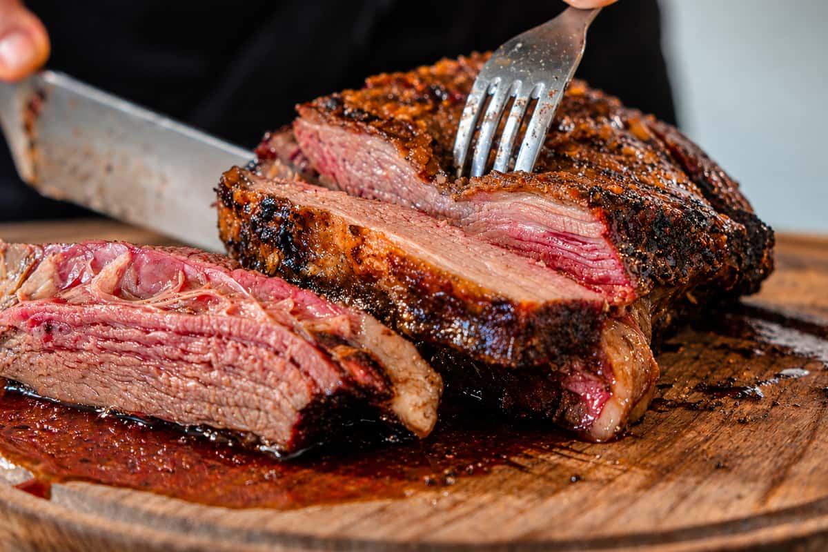 Cutting into smokey brisket on cutting board