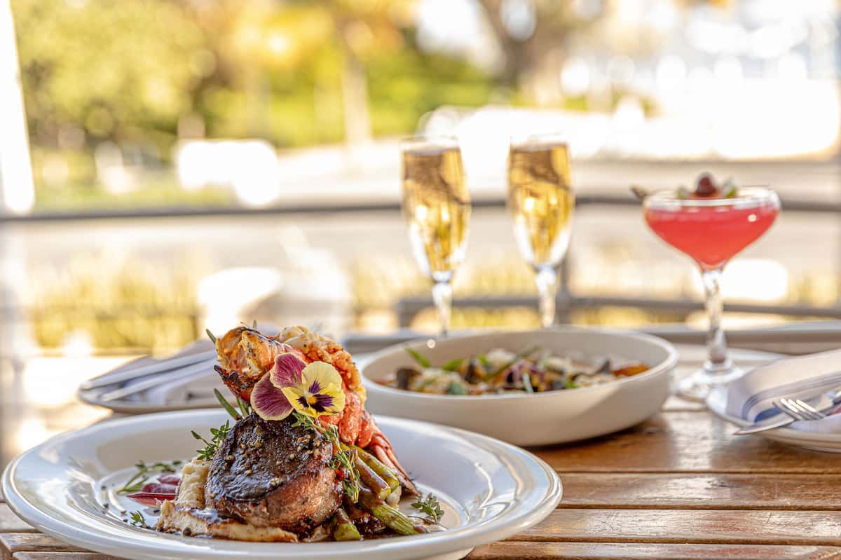 outdoor-dining.jpg Plated steak and lobster entrée with champagne and cocktails at an outdoor restaurant