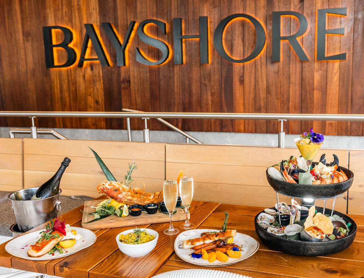 Bayshore Club seafood spread with champagne and raw bar selections in front of the Bayshore sign.
