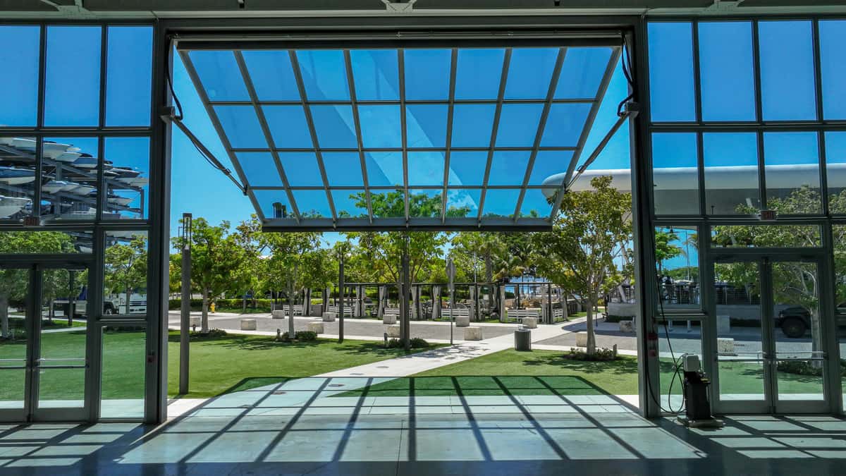 Modern glass-walled building opening onto a sunny landscaped courtyard near the marina.