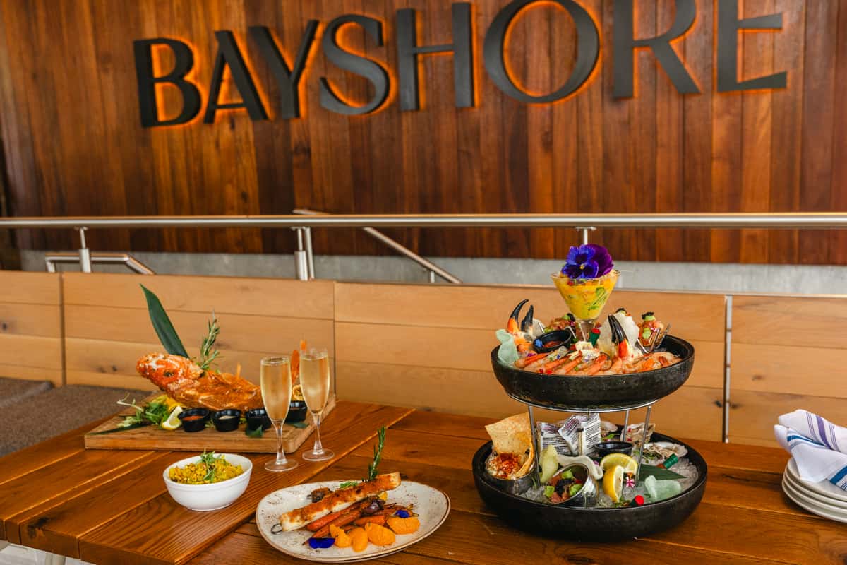 Bayshore restaurant table featuring a seafood tower, grilled fish dishes, lobster, and champagne.