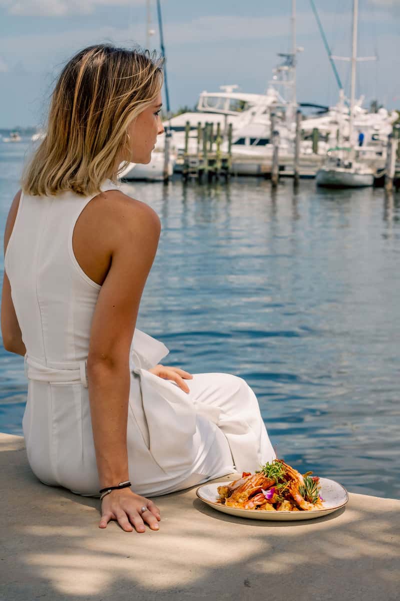 Woman enjoying waterfront dining beside a marina filled with boats in Miami