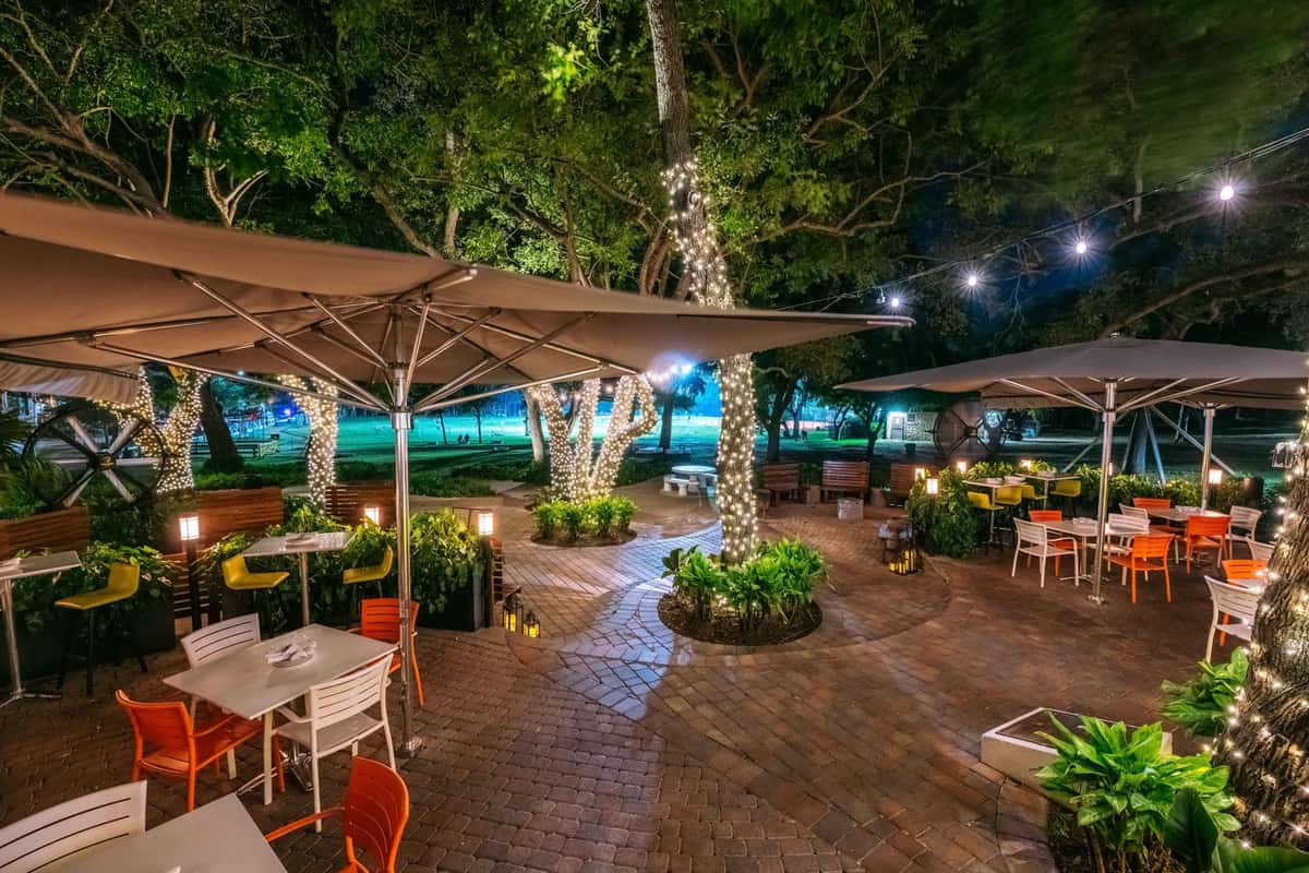 Glass & Vine outdoor seating area with lush greenery and dining tables under umbrellas