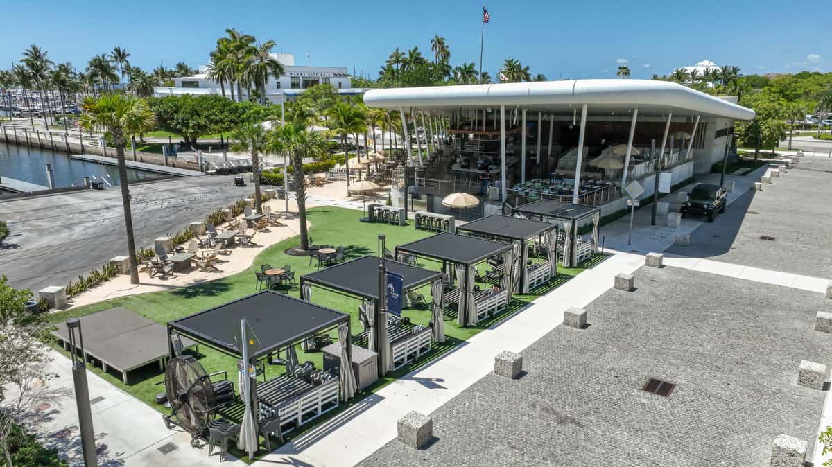 Waterfront tropical restaurant with outdoor cabanas, marina views, and patio seating