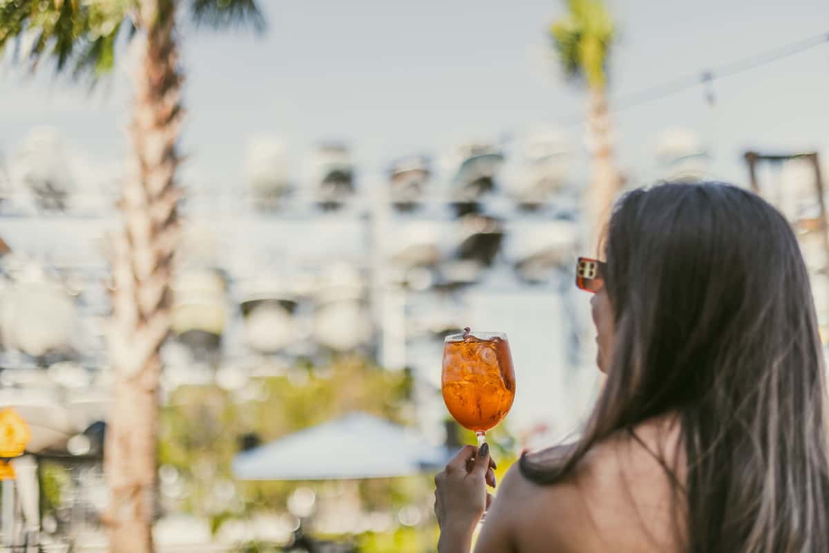Woman enjoying a cocktail at a tropical Coconut Grove waterfront venue.