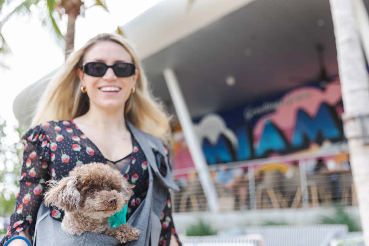 Woman carrying a small poodle outside a Miami restaurant