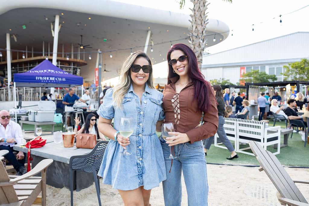 Two women holding wine glasses at an outdoor Miami restaurant event