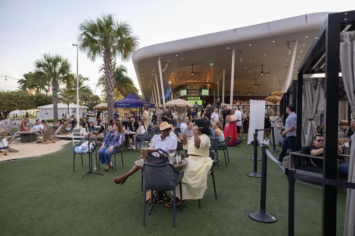 Bayshore Club outdoor dining area with guests seated on the lawn near the waterfront.