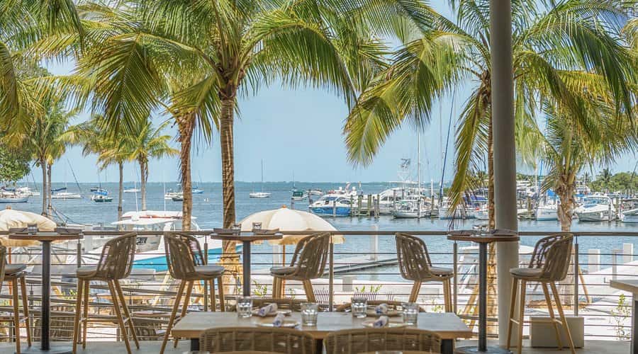 Exterior view of Bayshore Club waterfront restaurant with marina and palm trees