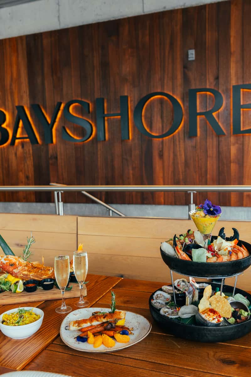 Luxury seafood spread with a tiered shellfish tower, grilled fish, champagne, and colorful sides at Bayshore.