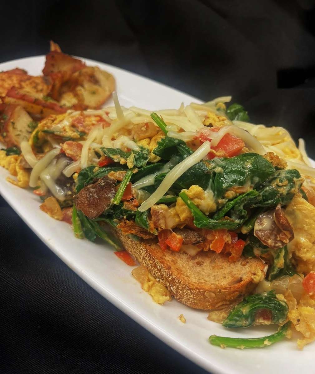 Golden, crispy toast layered with fresh greens, vibrant vegetables, and savory toppings, finished with a perfectly cooked egg for a rich and satisfying bite.