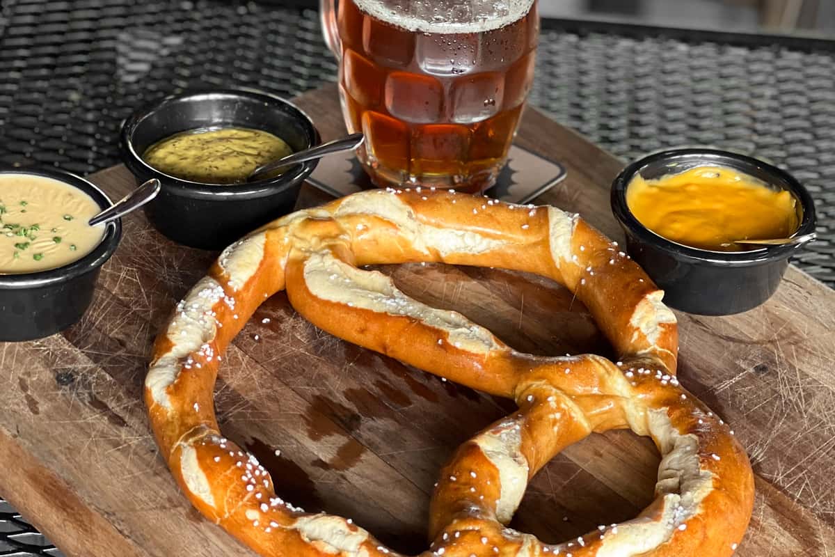 Soft pretzel with dip sauces and beer