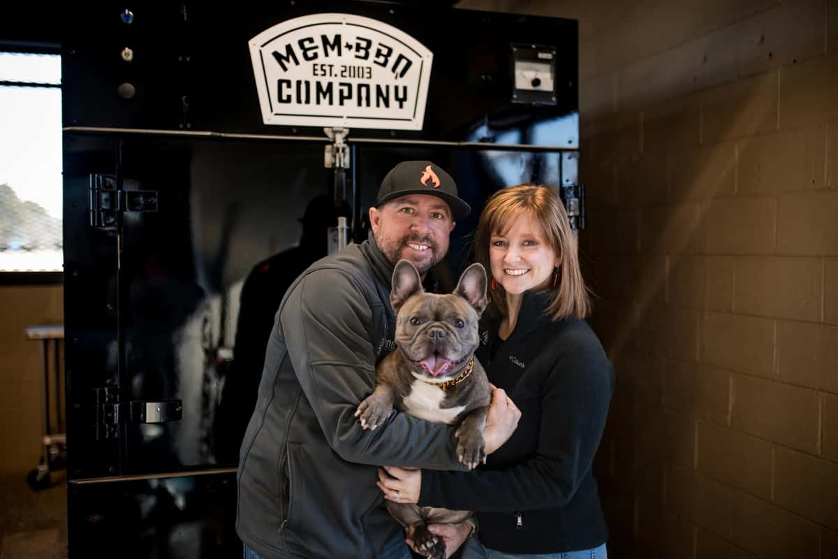 Redwood Smoke Shack owners standing in front of a barbecue smoker