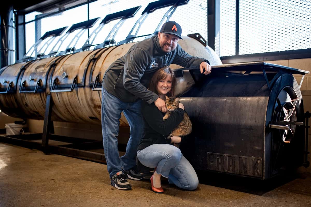 The owners of Redwood Smoke Shack standing in front of a smoker