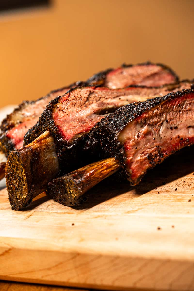 Large beef ribs on a wooden cutting board