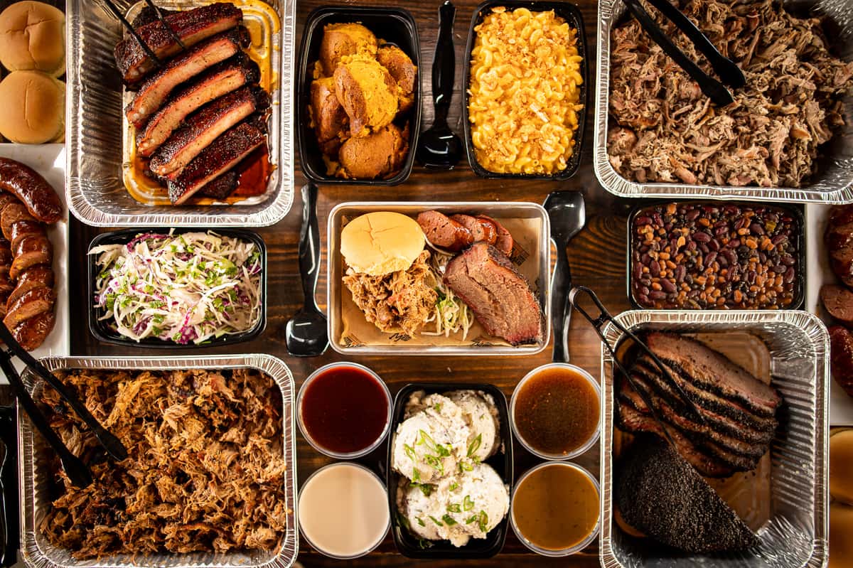 A table full of catered pans of barbecue, sides and fixins