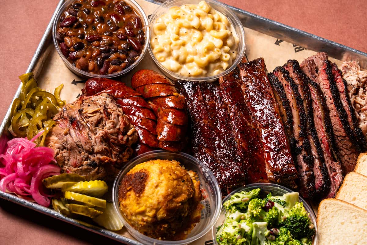 BBQ platter with sausage, brisket, ribs, pulled pork, broccoli salad, mac and cheese, and baked beans