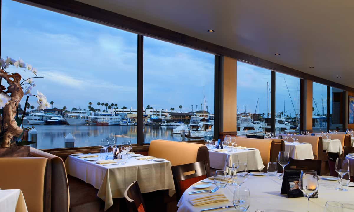 dining room with booths, table setting and a marina view