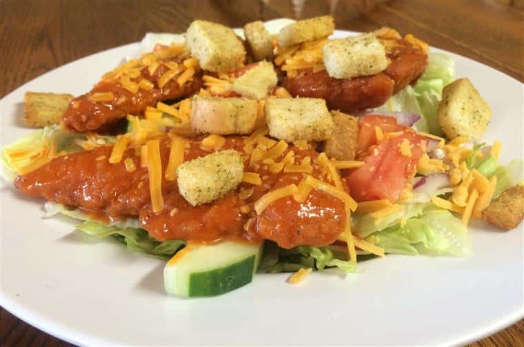 salad with lettuce, tomato, red onion, cucumber, croutons, shredded cheddar cheese and buffalo chicken