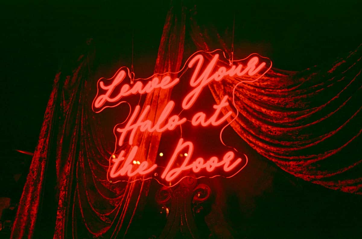 Neon sign that says leave your halo at the door