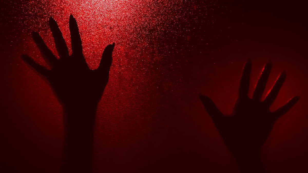 Silhouetted hands reaching up on a textured red-lit background, evoking mystery and drama.