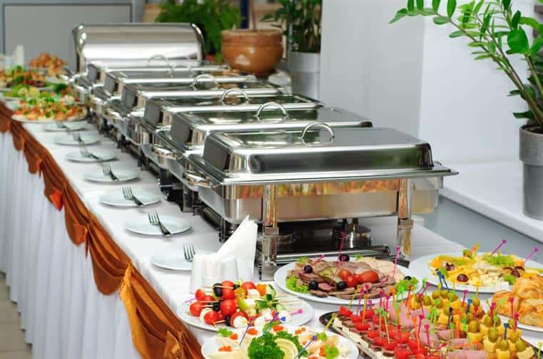 An assortment of finger foods on a table next to silver catering trays