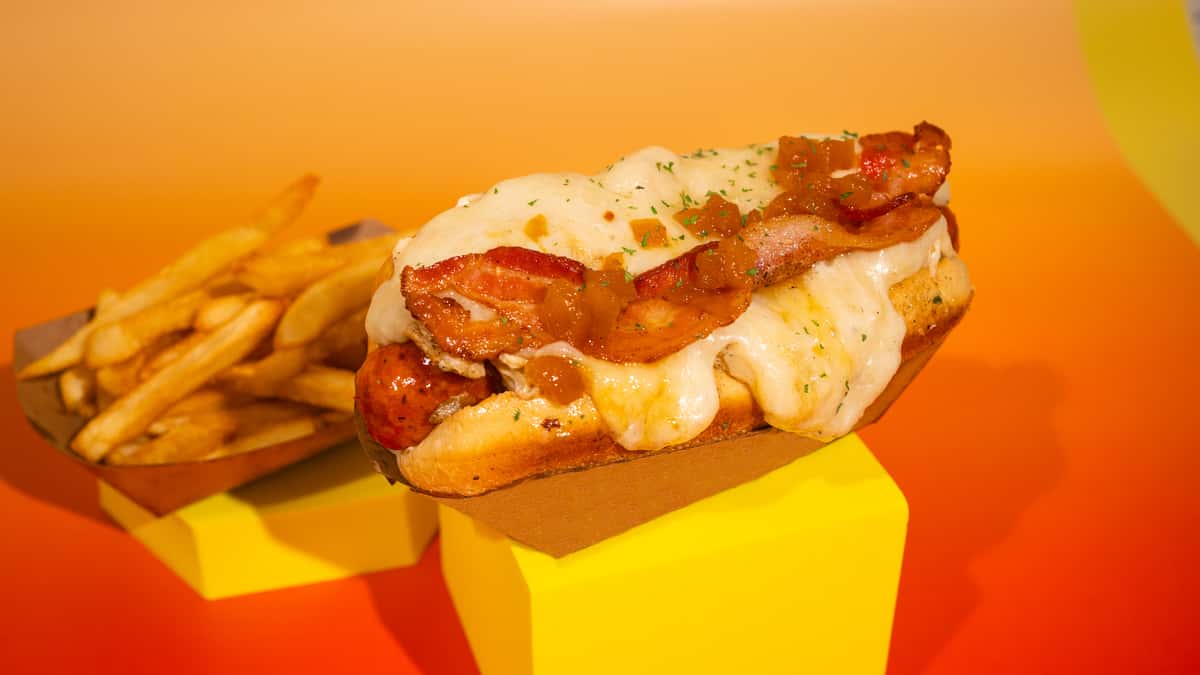 A hot dog with smoked chorizo and a hint of spice, shredded chicken in sauce, grilled onions, pineapple sauce, cheese, and smoked bacon. ALL OUR BURGERS AND HOT DOG ARE SERVED WITH FRIES! Perro Caliente con chorizo ahumado y un toque de picante, pollo desmechado en salsa, cebolla a la parrilla, salsa de piña, queso y tocino ahumado. TODAS NUESTRAS BURGERS Y PERROS VIENEN CON PAPAS A LA FRANCESA INCLUIDAS