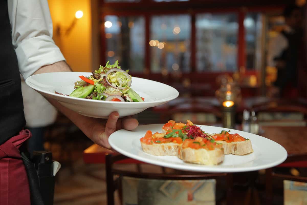 Waitress' hands holding two plates of food