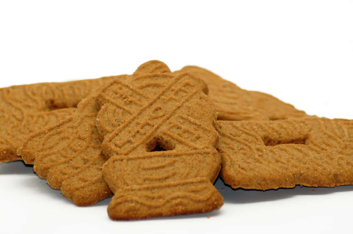Several spice cookies are stacked on a white surface. The cookies are embossed with a traditional Dutch windmill design and the text "Speculaas".