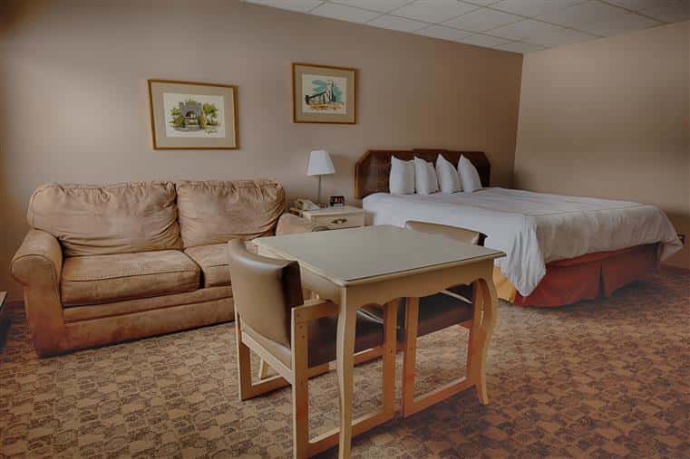 hotel room with a queen bed, a table and couch