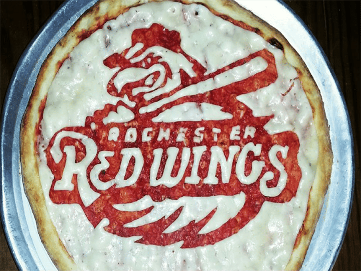 A pizza crust with the rochester redwings logo carved in it