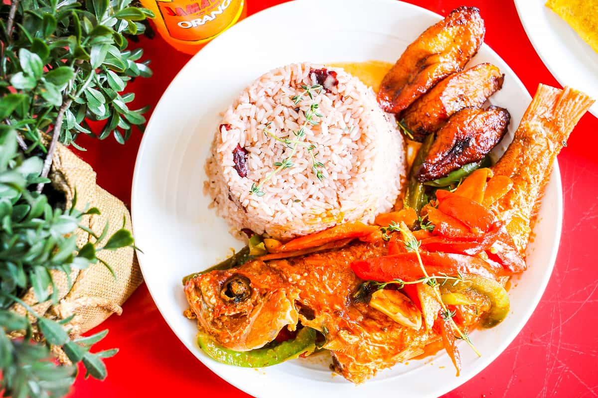 Grilled fish topped with onions and peppers, served with fried plantains and lime. Vibrant and flavorful.