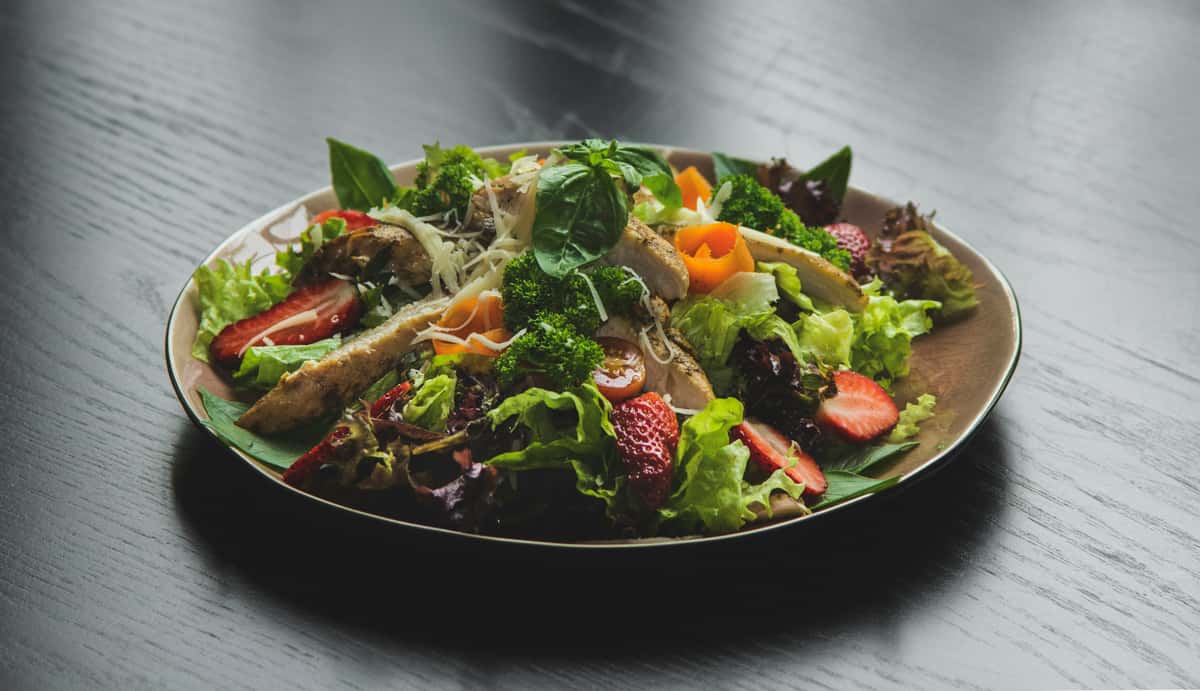 Mixed greens topped with grilled chicken, fresh strawberries, broccoli, shaved cheese, and basil—light, fresh restaurant salad option.