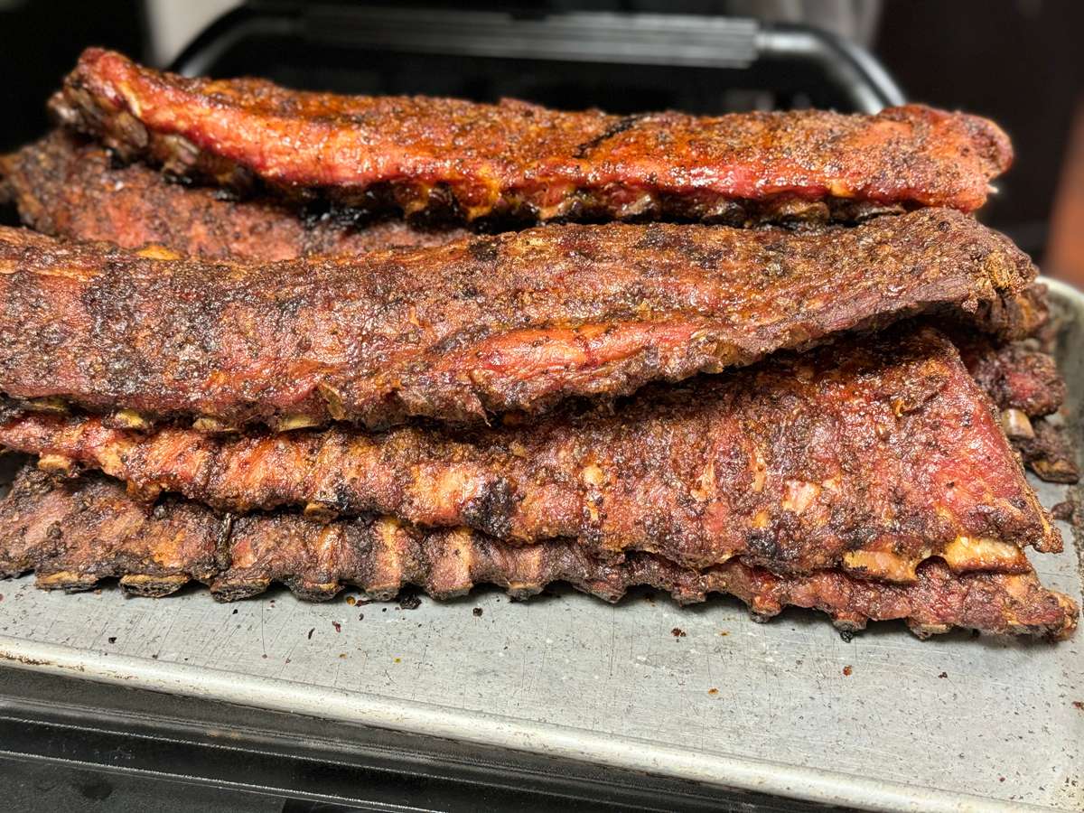 Stack of dry-rubbed pork ribs with a smoky bark, fresh from the pit, showcasing a rich, seasoned crust ideal for barbecue purists.