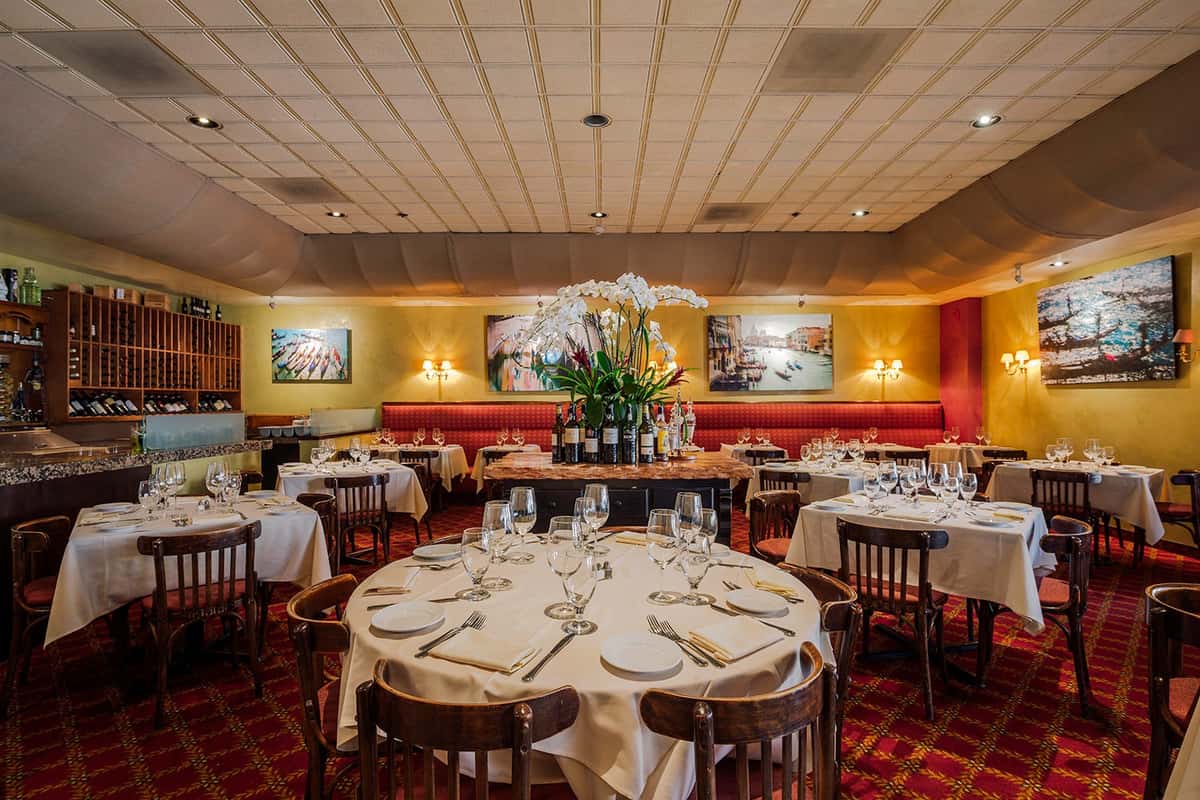Elegant Italian dining room with round tables and warm ambiance at Celestino Pasadena