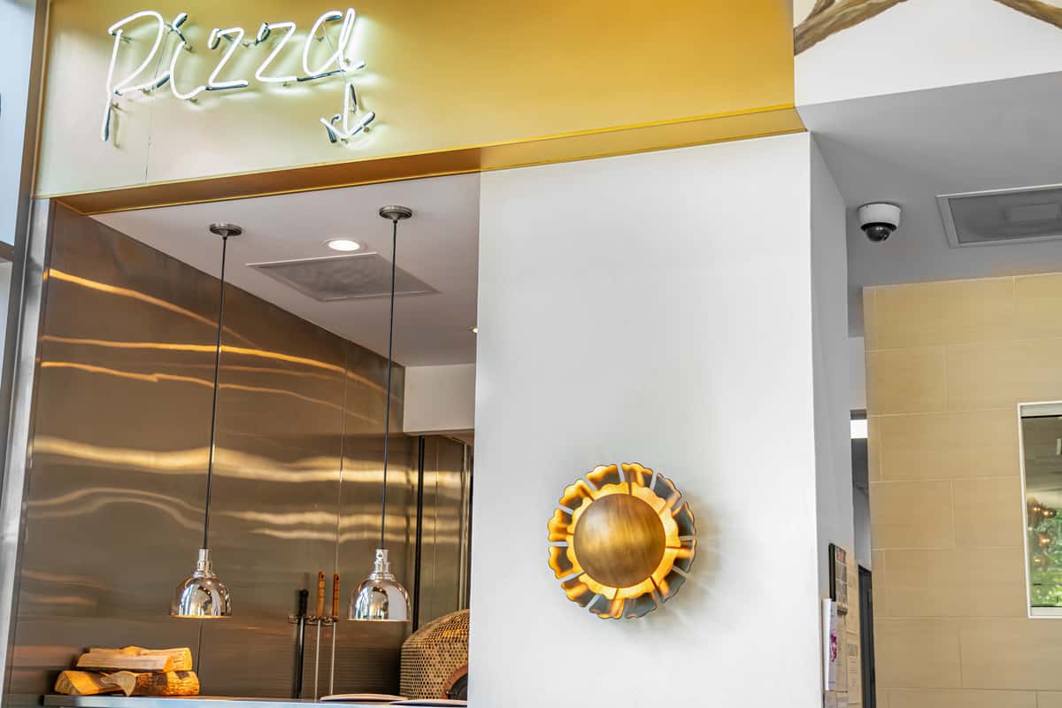 pendant lights and gold sun wall art with neon pizza sign