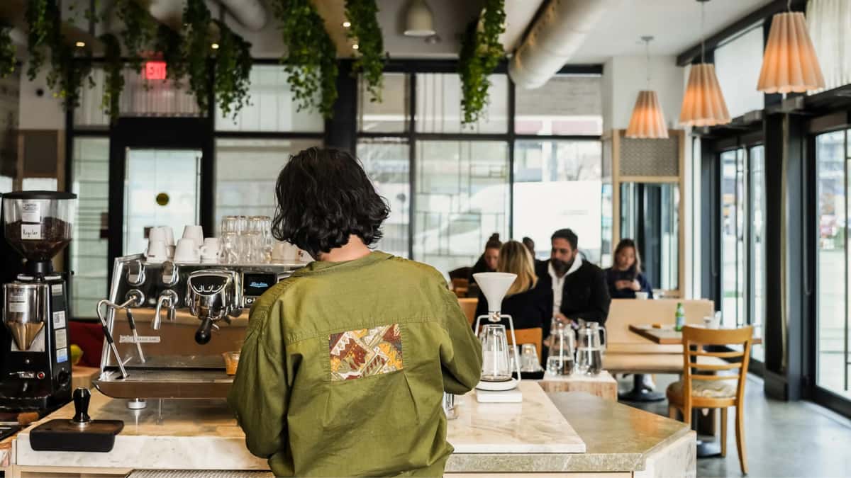 A Café ZUZU Pizzeria employee standing behind the counter