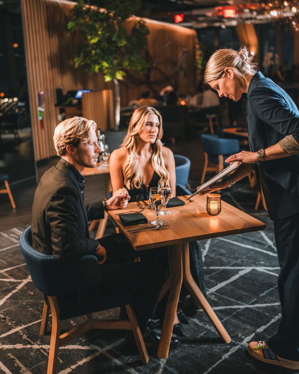 Sommelier at 71Above presenting the wine list to guests, guiding pairings for a fine dining experience with skyline views in Los Angeles