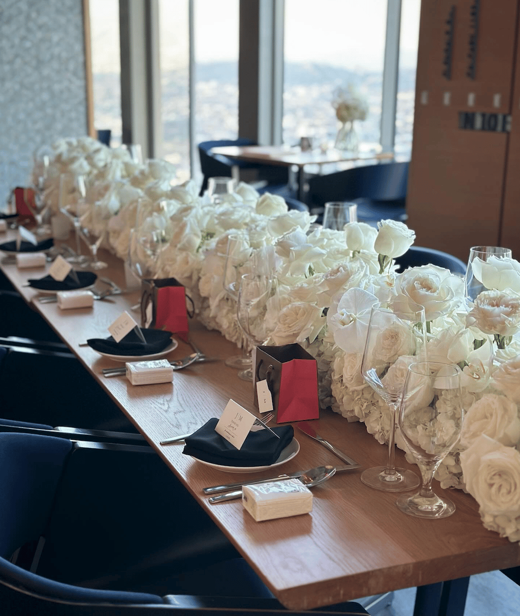 Private dining table at 71Above decorated with white floral arrangements by Petal Relations, overlooking Los Angeles skyline.